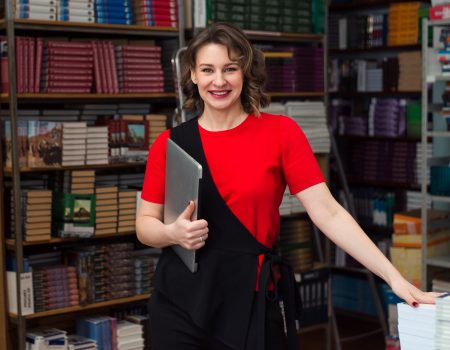 teacher-or-business-professional-standing-in-workplace-with-book-shelves-background-looking-at-camera_t20_X38nWV